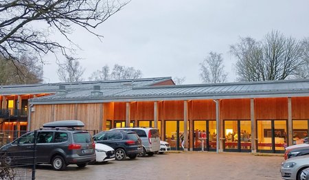 Ein modernes hell erleuchtetes Gebäude an einem Parkplatz.