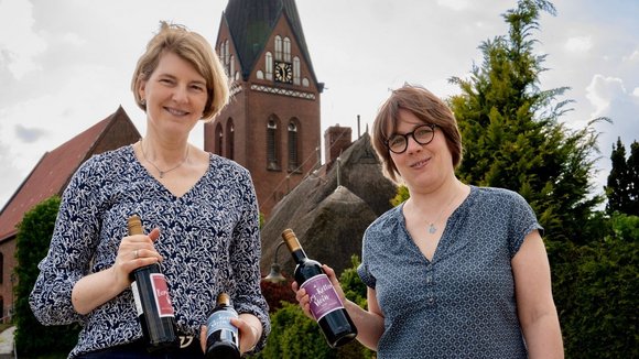 Zwei Menschen mit Flaschen vor einer Kirche 