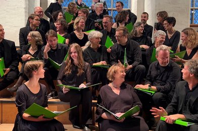 Eine Gruppe von Chrsängerinnen und Chorsängern auf dem Chorpodest in der Aegidienkirche Lübeck - Copyright: Phemios Kammerchor