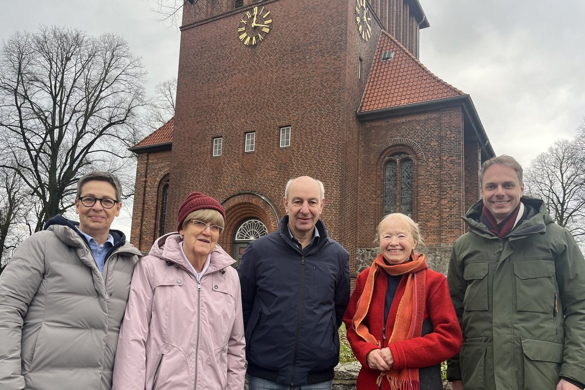 Drei Frauen und zwei Männer stehen im Winter vor einer Kirche.