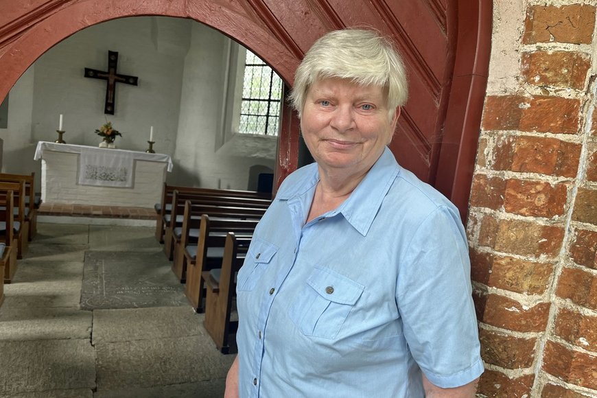Eine Frau mit kurzen grauen Haaren steht vor dem Eingang einer Kapelle. - Copyright: Annkathrin Bornholdt