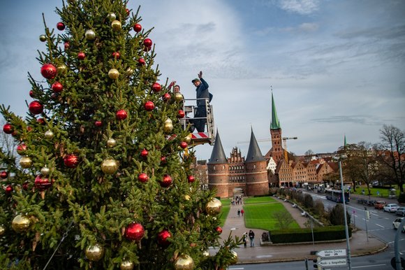 Eine Frau hängt eine Weihnachtsbaumkugel in einen Baum