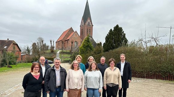 Mehrere Personen im Vordergrund, im Hintergrund Kirche