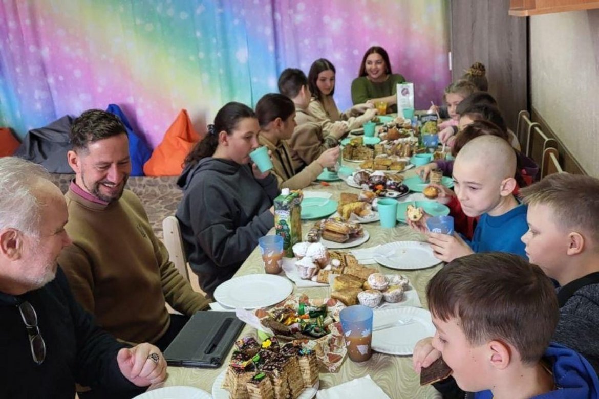 Pastor und Kinder sitzen am Tisch