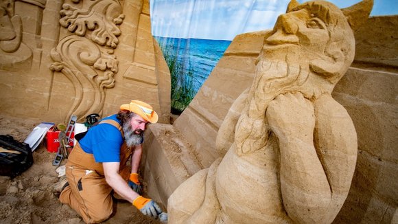 Ein Mann schnitzt eine Sandfigur