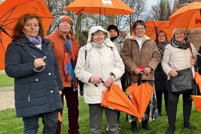 mehrere Frauen mit orangefarbenen Schirmen - Copyright: Ev. Frauenwerk