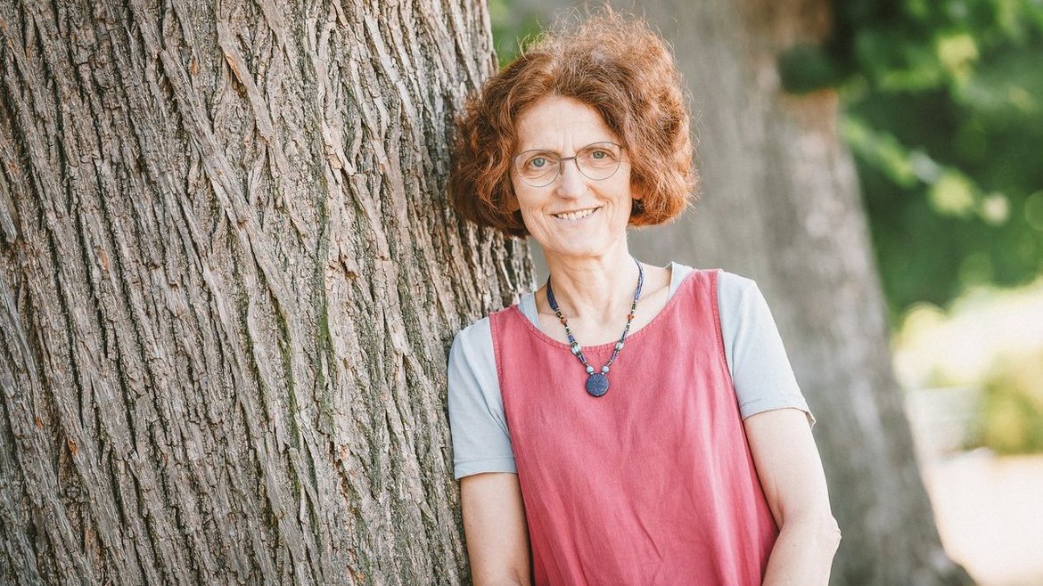 Pastorin Elisabeth Hartmann-Runge lehnt an einem Baum 